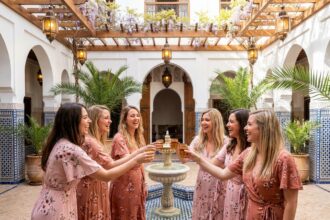 Groupe de femmes en EVJF fêtant dans un riad traditionnel de Marrakech entouré de zellige et de fontaines en mosaïque